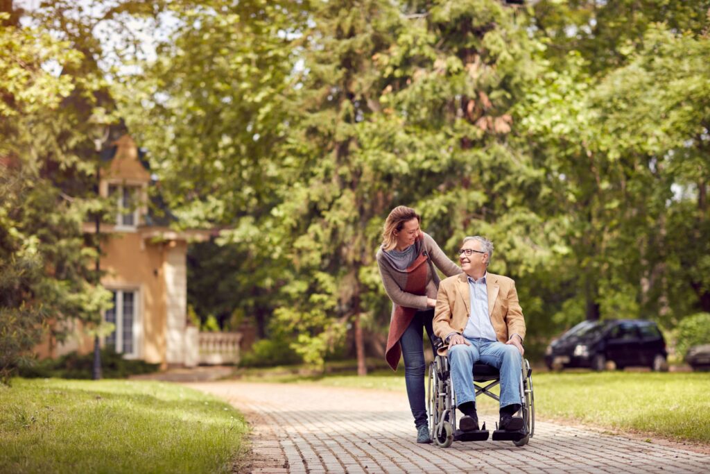 Arzthelferin hilft einem Mann im Rollstuhl